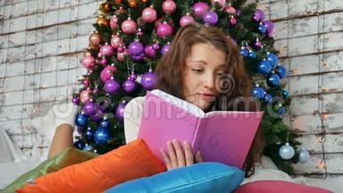 年轻的黑发正在阅读一本关于优雅圣诞树背景的书。 非常规色，创意